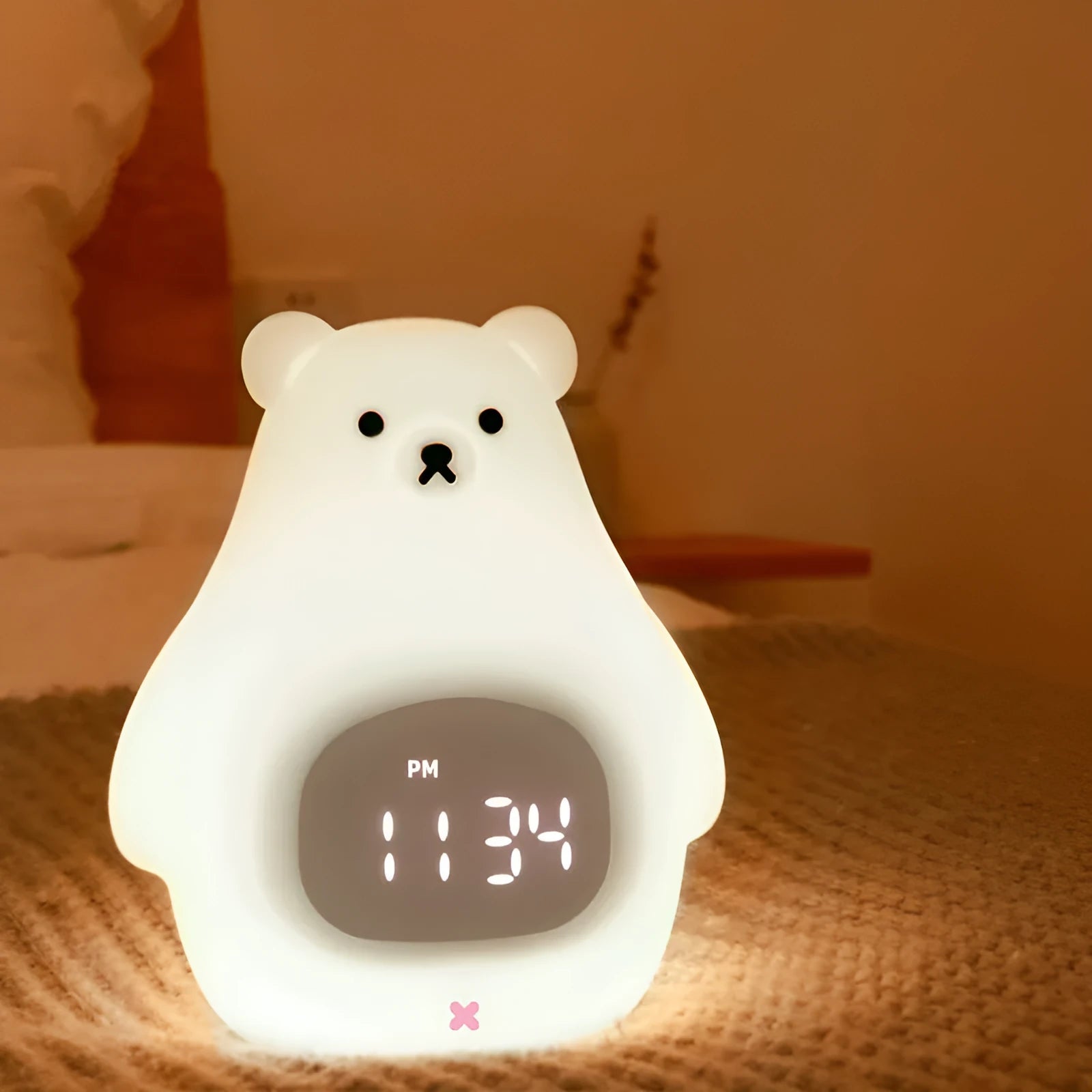 White silicone cartoon bear-shaped night light with remote control on a bedside table.