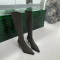 Women's black pointed toe stiletto heel boots with a back zipper, showing the below-the-knee shaft.