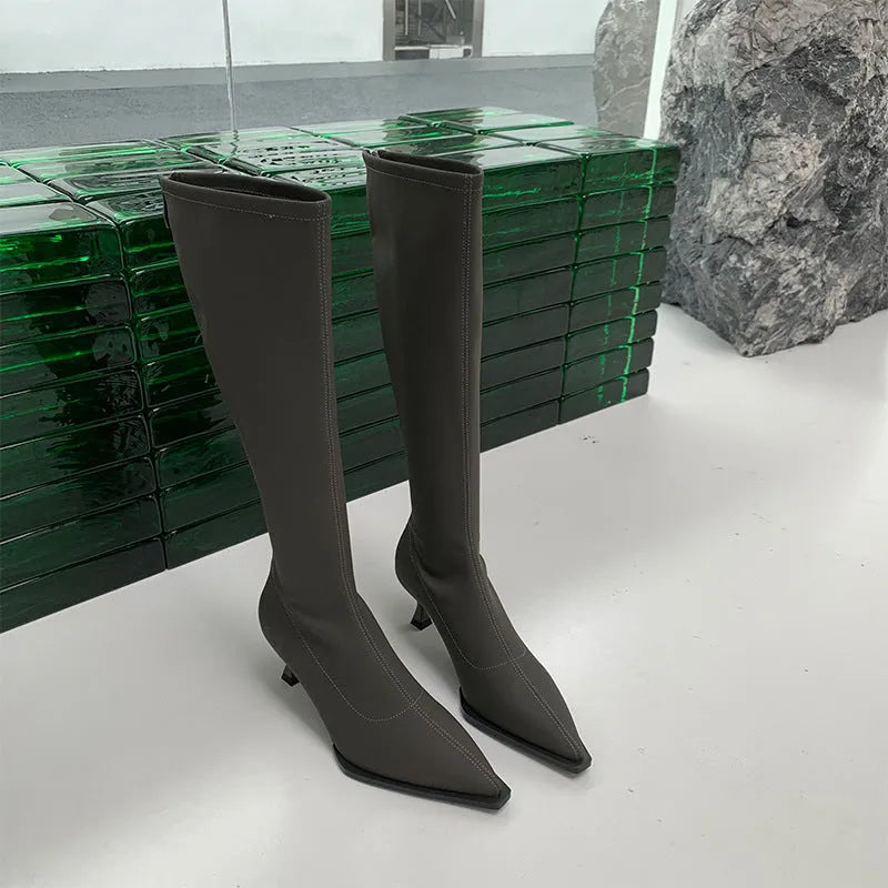Women's black pointed toe stiletto heel boots with a back zipper, showing the below-the-knee shaft.