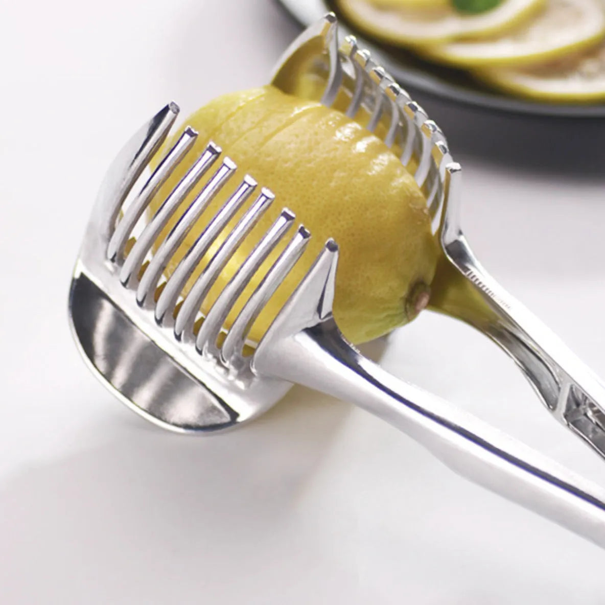 Silver plastic foldable lemon slicer kitchen gadget shown cutting citrus fruit