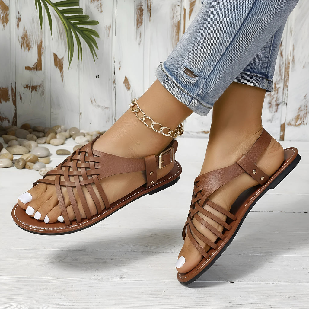 Black Roman style cross strap buckle beach slippers with open toe and leather lining.