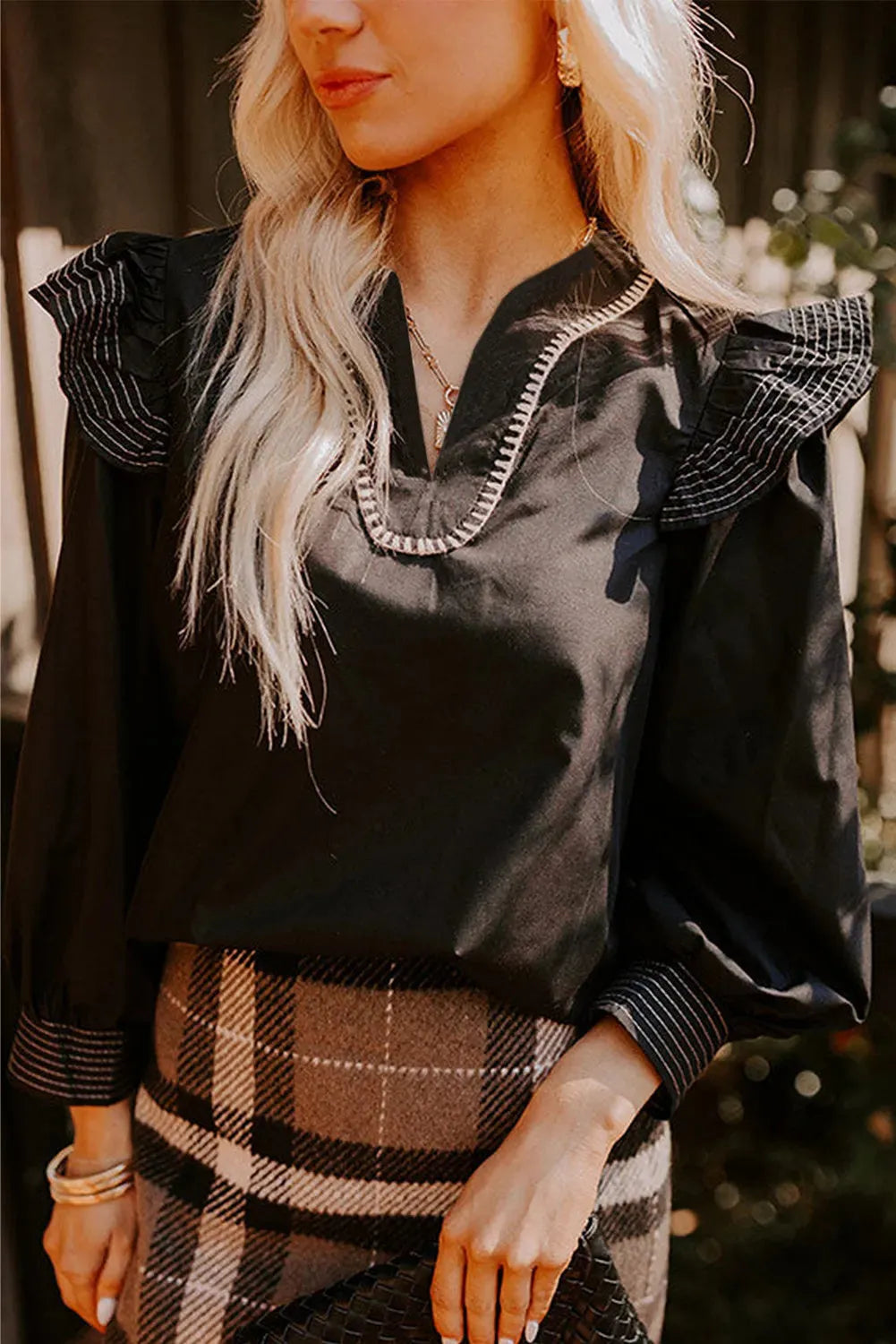 Black V-neck long sleeve blouse with contrast stitching and ruffle detail on sleeves.