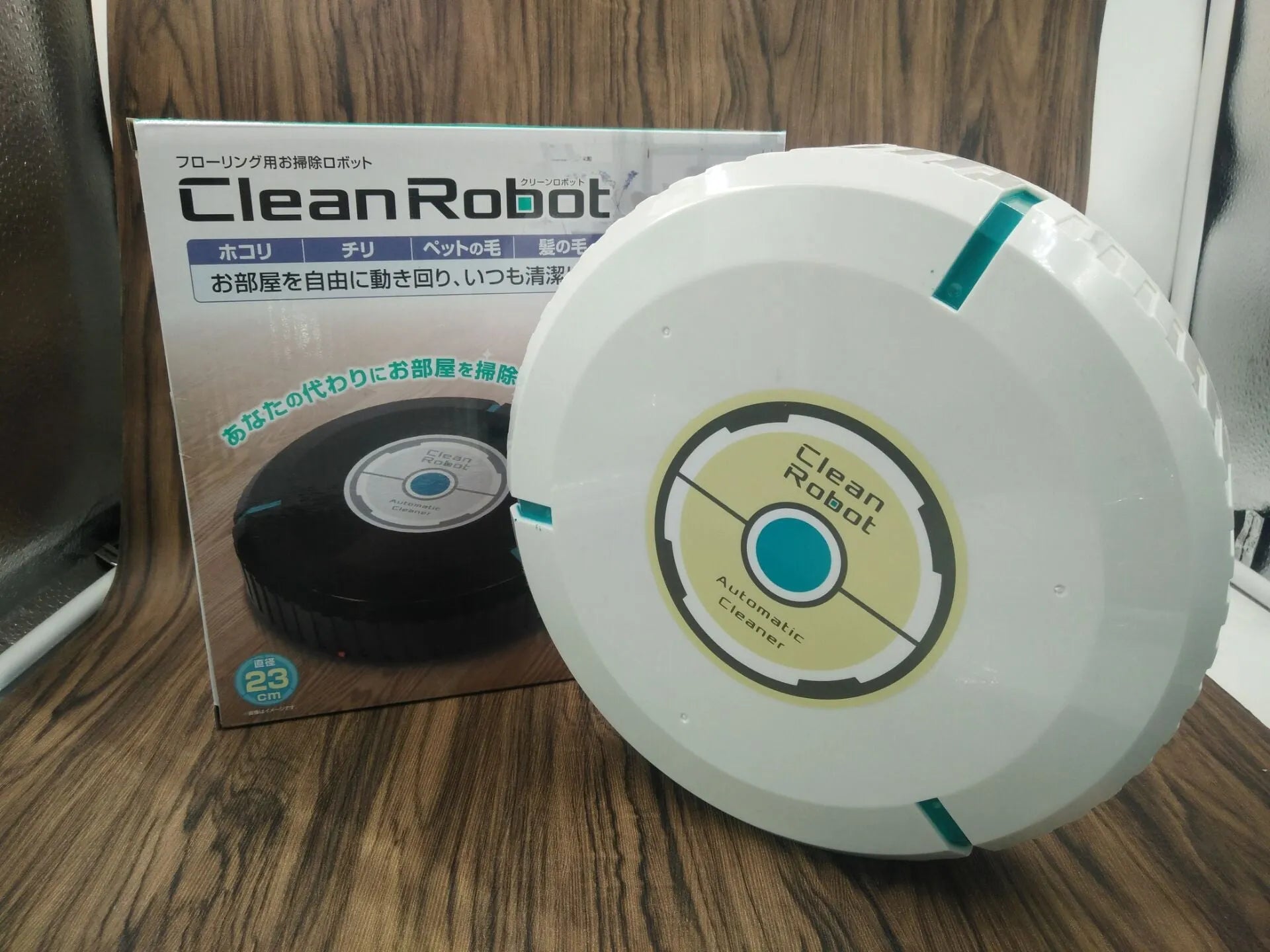Black or white automatic robot vacuum cleaner with wide cleaning head on wooden floor.
