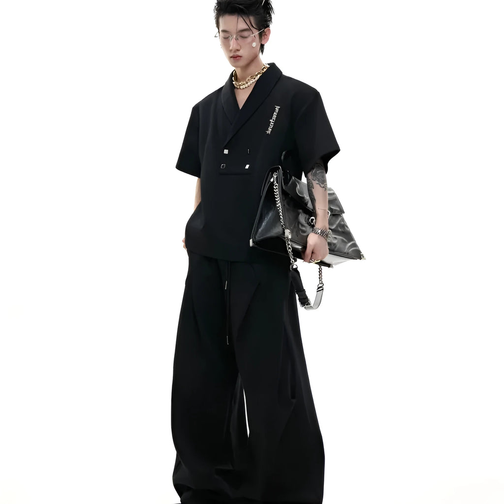 Men's dark grey v-neck sports jacket with padded shoulders and metal details, worn with matching shorts.