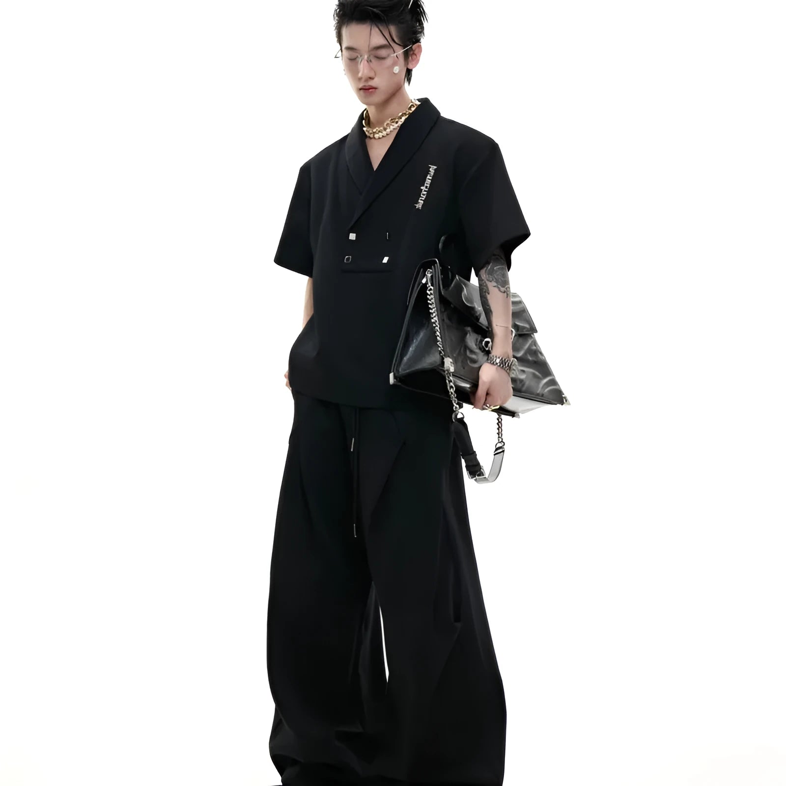 Men's dark grey v-neck sports jacket with padded shoulders and metal details, worn with matching shorts.