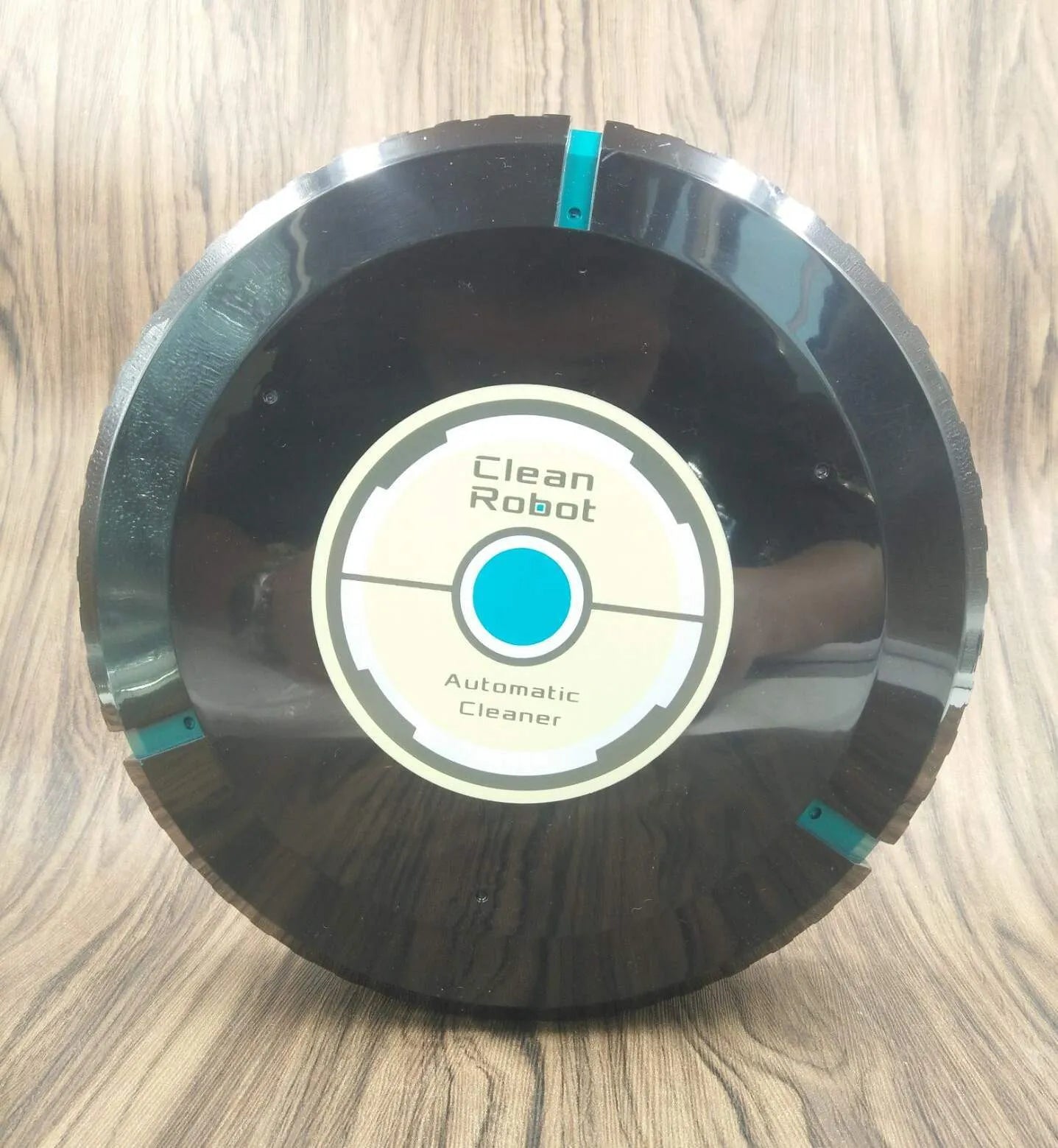 Black or white automatic robot vacuum cleaner with wide cleaning head on wooden floor.