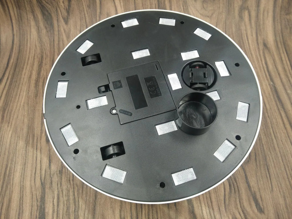 Black or white automatic robot vacuum cleaner with wide cleaning head on wooden floor.