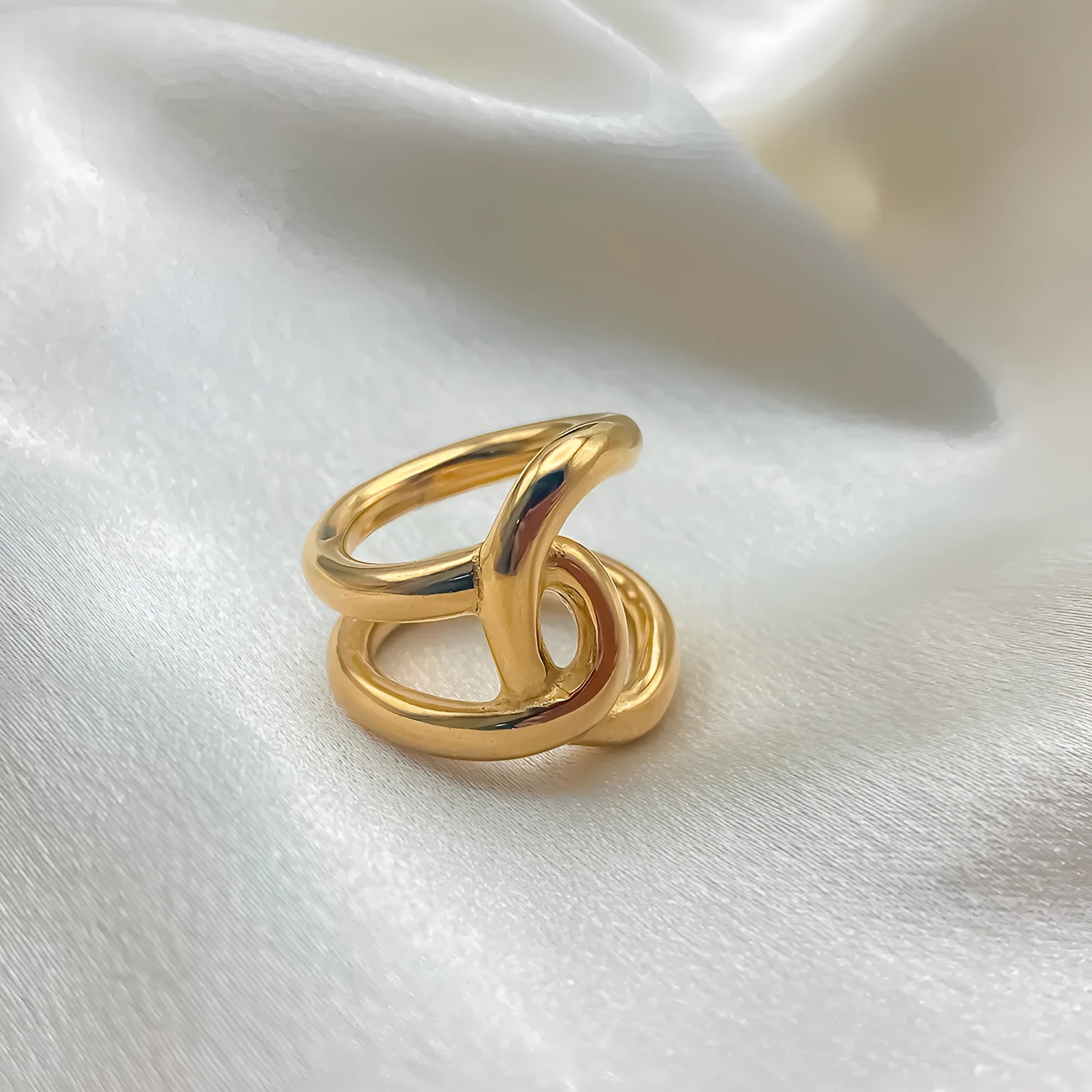 Adjustable knotted opening ring in stainless steel, shown in both gold and steel colour finishes on a woman's hand.