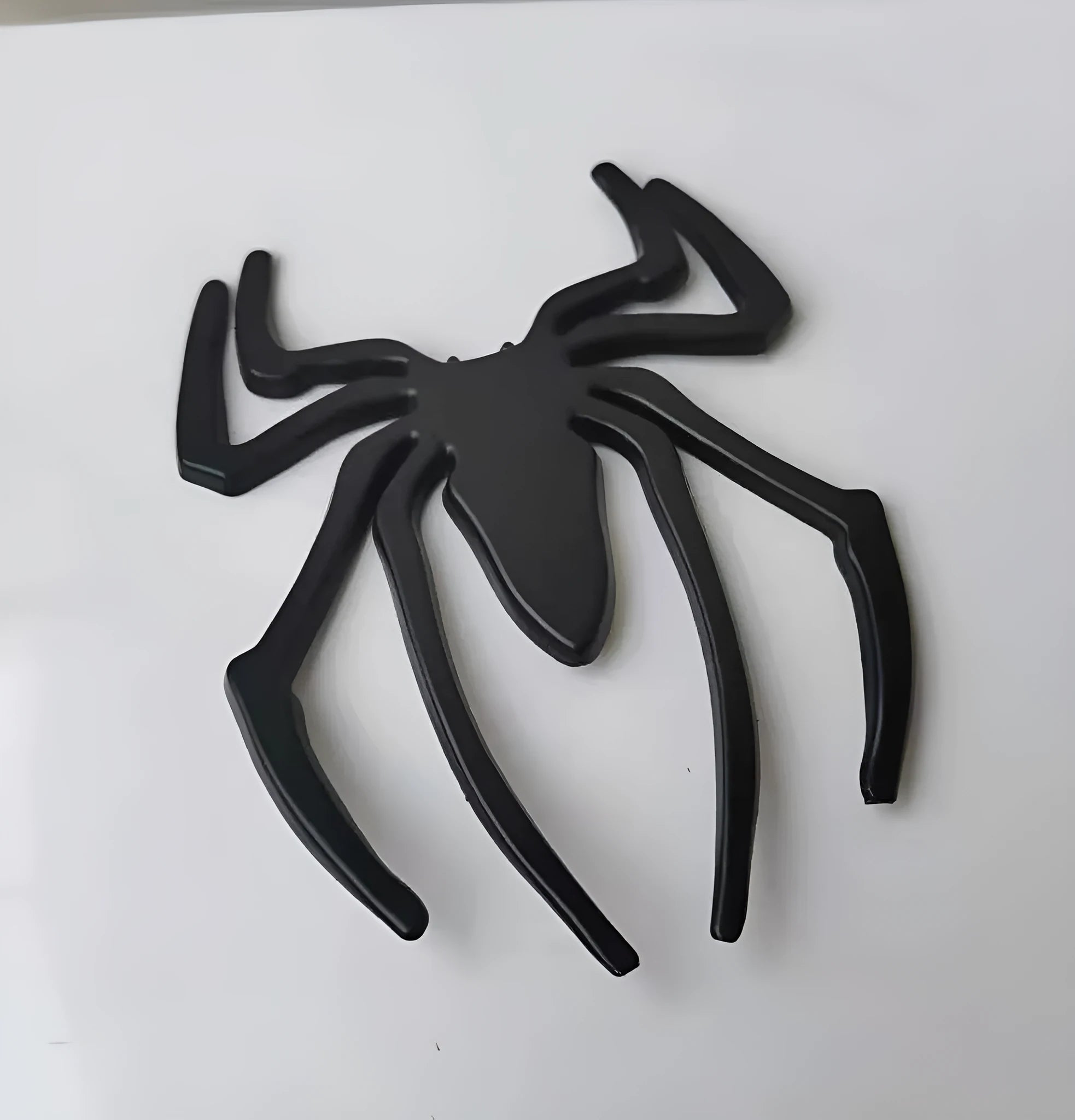 Three-dimensional metal spider car sticker in zinc alloy on a vehicle bumper.