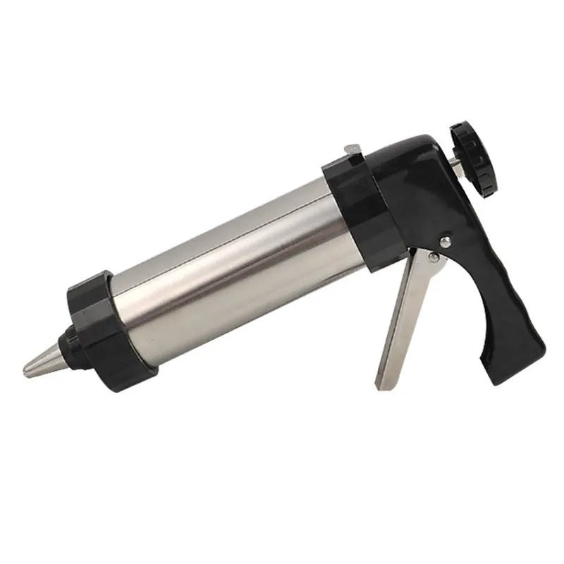 Stainless steel biscuit press gun with assortment of cookie moulds and piping nozzles on a baking sheet.