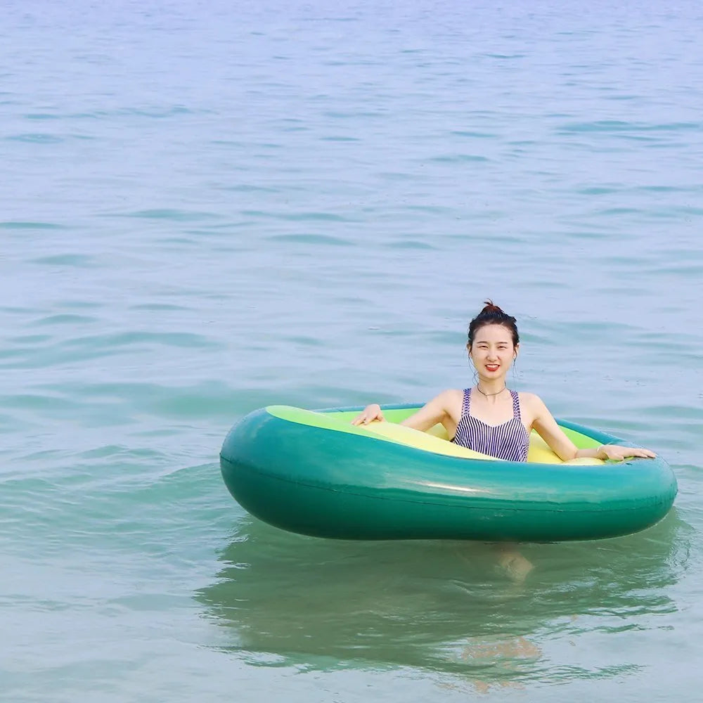 Large green inflatable avocado pool float on blue water, showing its 169cm length.