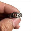 Close-up of a hand-forged copper Buddha ring with grotto design and rock texture on a size 8 finger.