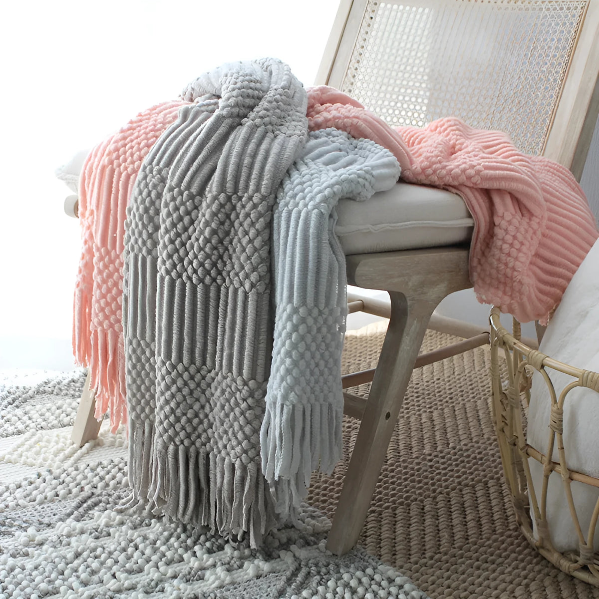 Nordic knitted bubble blanket in acrylic and polyester fibre, 127x170cm, shown as a plain sofa throw in light grey, light khaki, or pink.