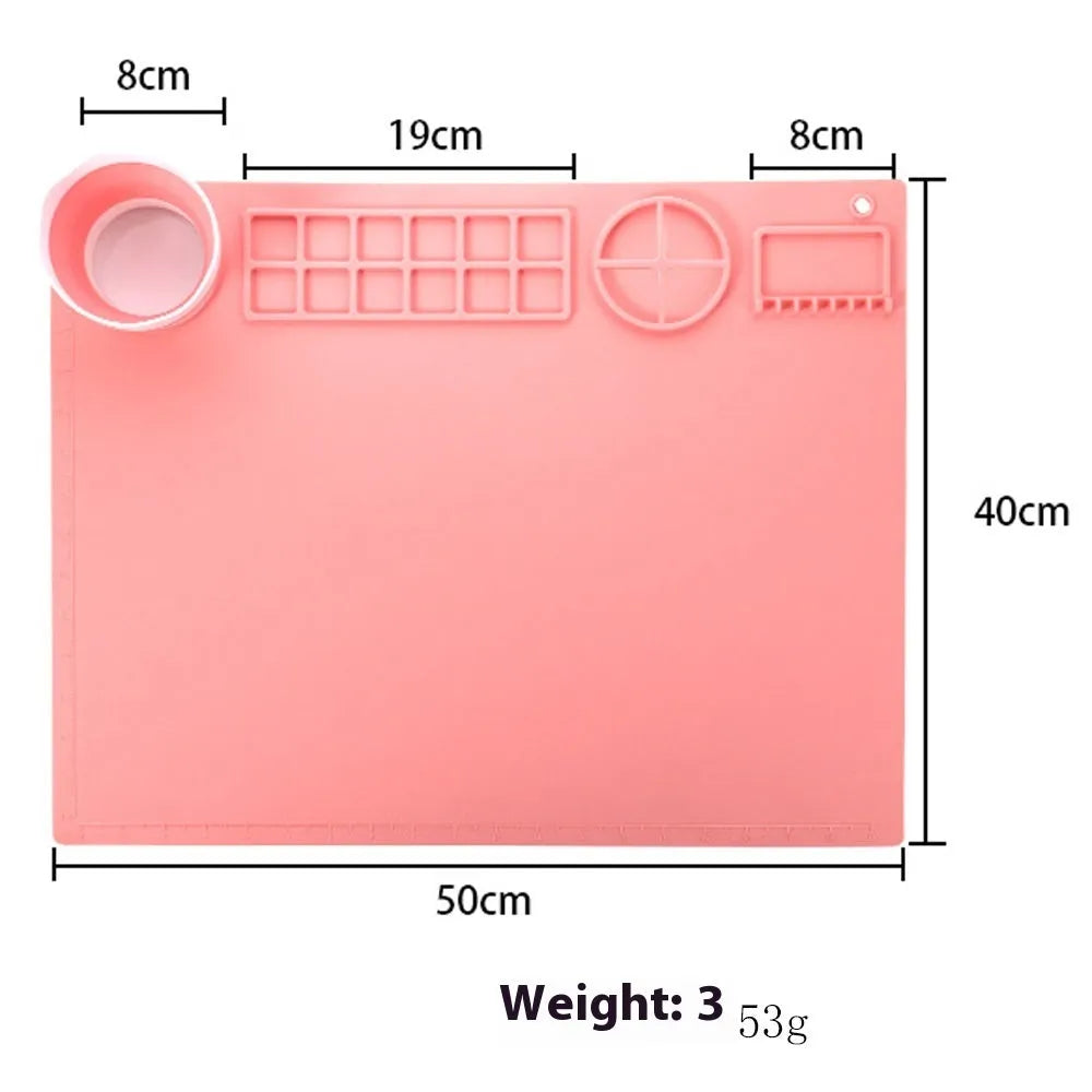 Light blue silicone painting mat with two bowl compartments on a wooden table.