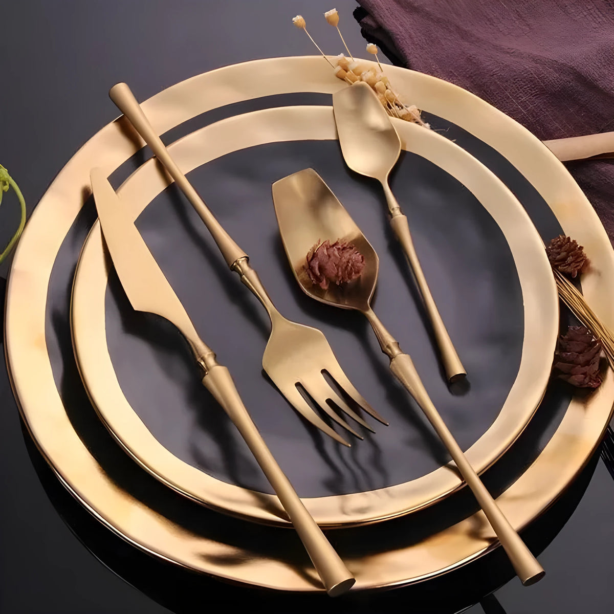 Stainless steel cutlery set with gold finish including knife, fork, spoon, and teaspoon on table