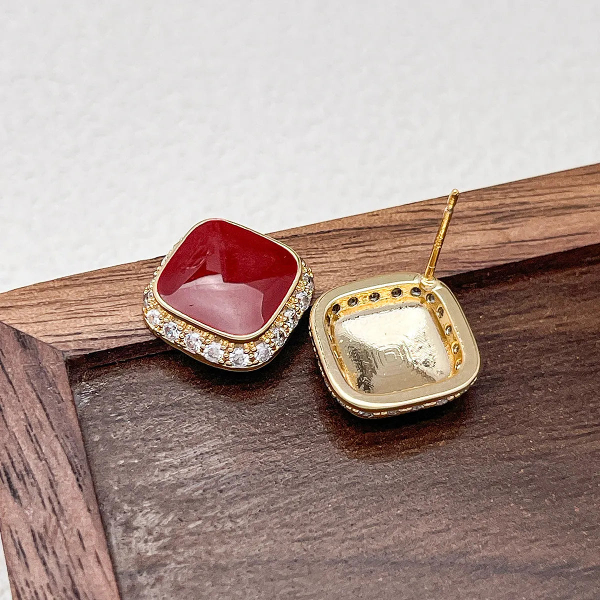 Red alloy square earrings with an inlaid geometric pattern, shown from the front.