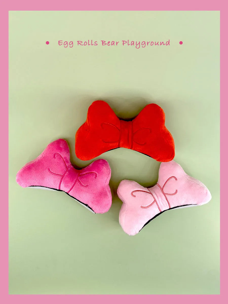 Soft plush bow tie helmet decoration in red, peach pink, and rose pink for motorcycle and ski helmets.
