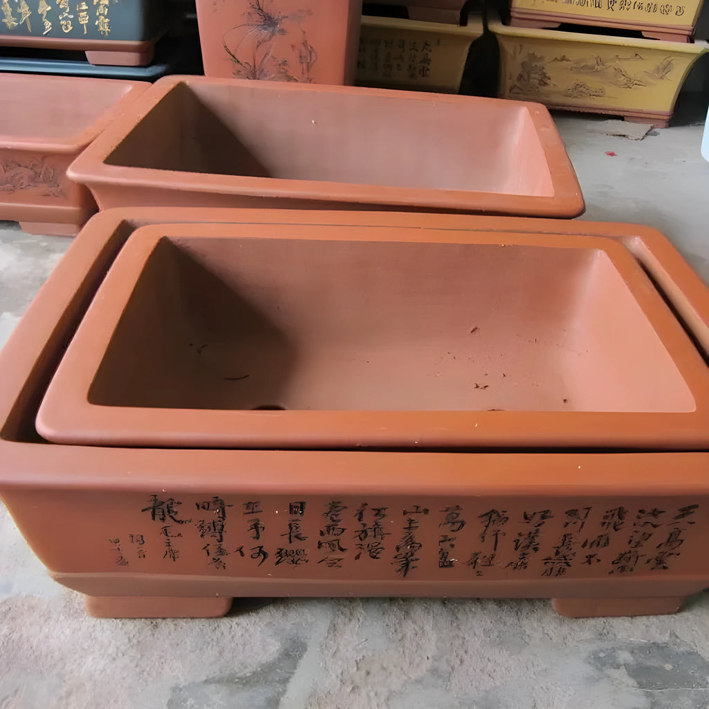Two Yixing purple clay rectangular flower pots in different sizes on a wooden surface