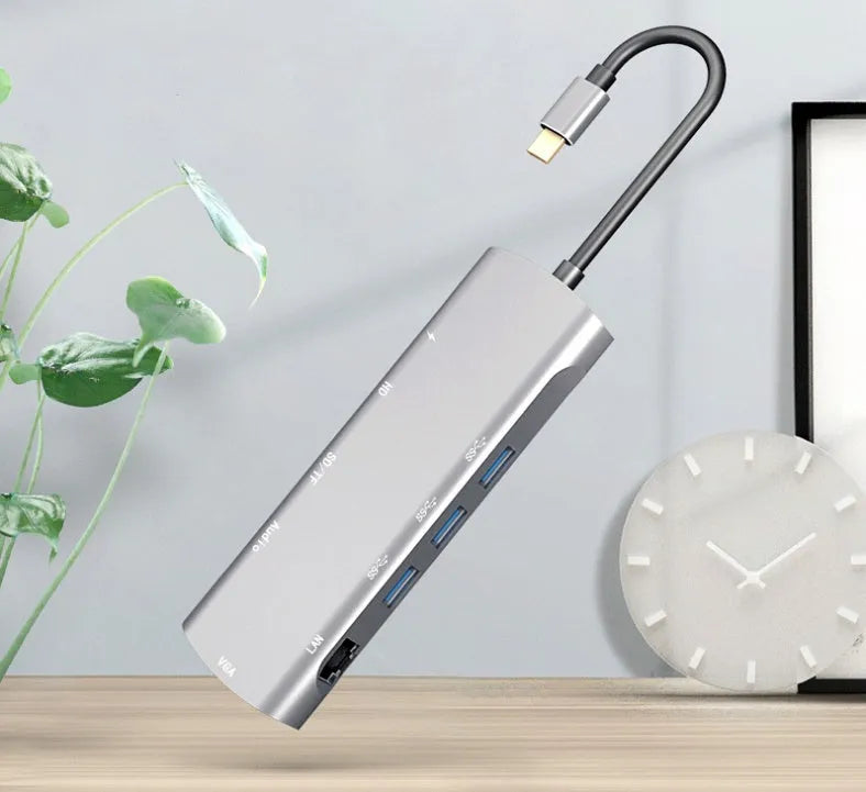 Grey aluminium alloy USB-C docking station with HDMI, VGA, USB ports, and a card reader.