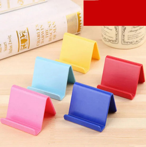 Small plastic mobile phone stand in blue, size 6x4.5cm, on a wooden desk