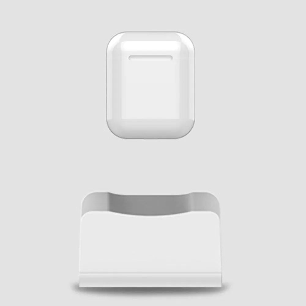 White headphone charging base station on a desk, holding a pair of over-ear headphones.