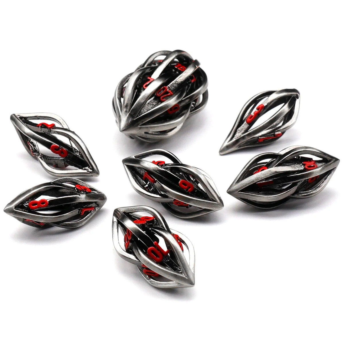Seven metal melon seed shape dice in antique silver with coloured characters on a surface