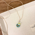 Women's pendant necklace with a coloured glaze skirt-shaped joker charm on a cotton and linen clavicle chain.
