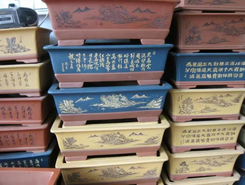 Two Yixing purple clay rectangular flower pots in different sizes on a wooden surface