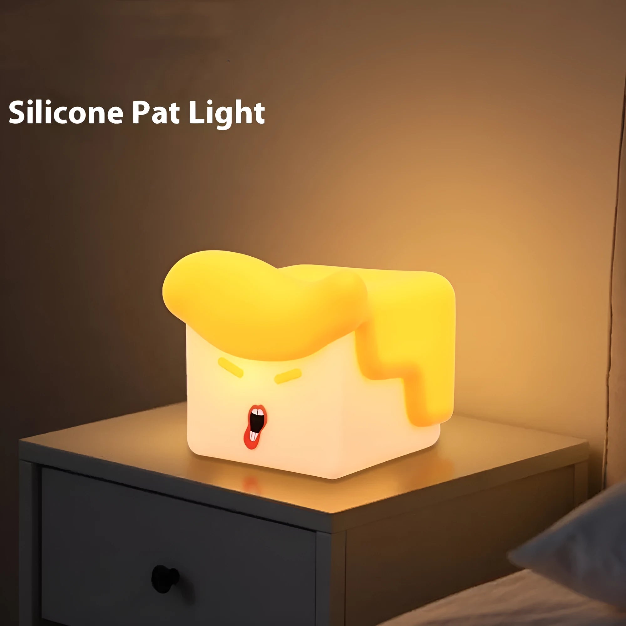 Yellow soft silicone pat lamp with USB charging port on a wooden table showing night light glow