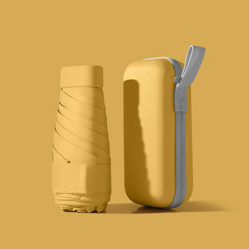 Ultra-light six-fold flat sun umbrella in sky blue with a rubber handle, shown with its capsule storage box.