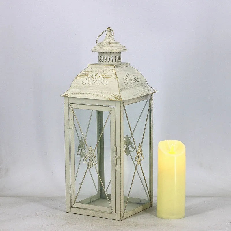 Black and white wrought iron floor standing storm lantern with tempered glass panels on a patio.