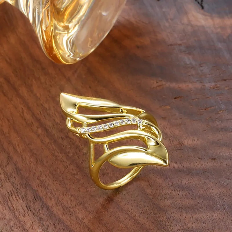Women's gold-colour ring with exaggerated curved design on finger, showing profile and zircon finish