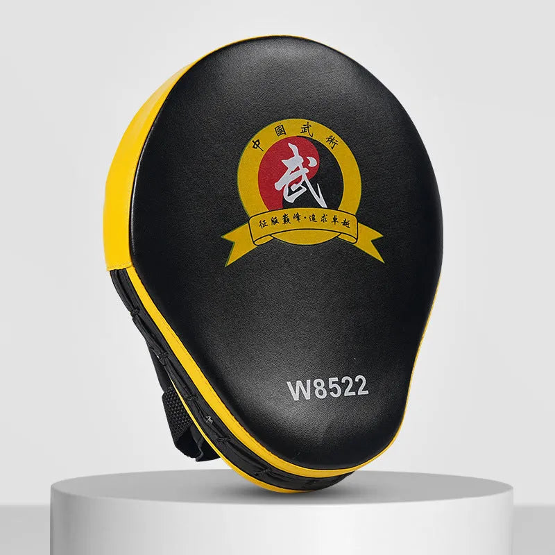 Red and black curved boxing punch mitts held in a trainer's hands for Muay Thai or Sanda practice.