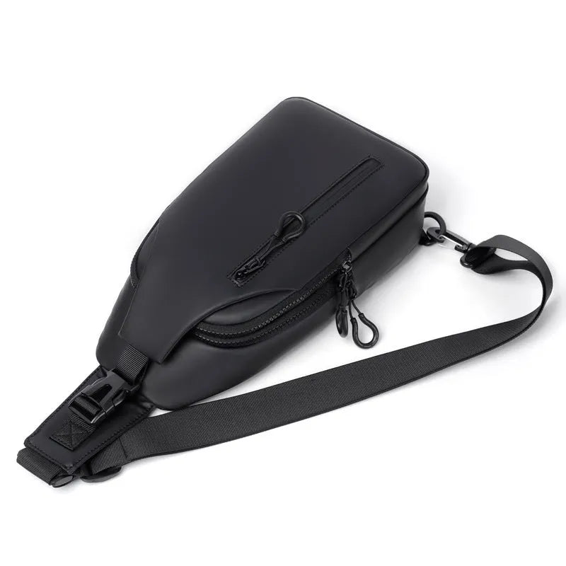 Black sling crossbody chest bag for men with zipper closure and stitched detail on a white background