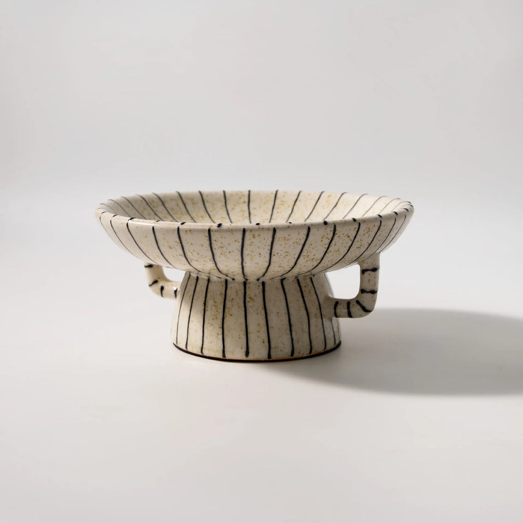 Black and white striped synthetic resin fruit plate on a wooden surface.