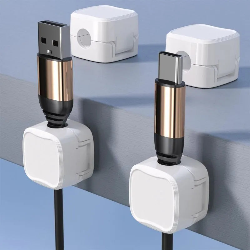 White and black magnetic cable clips holding a USB cable against a wooden desk edge.