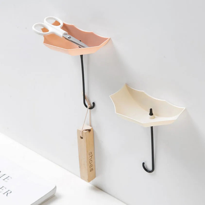 3 plastic umbrella-shaped sticky hooks in Nordic pink blue green, on a white door, holding keys