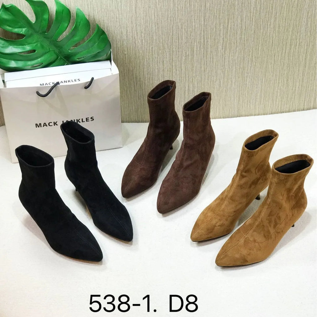 Black microfiber ankle boots with a stiletto heel and pointed toe on a mid-calf sock.
