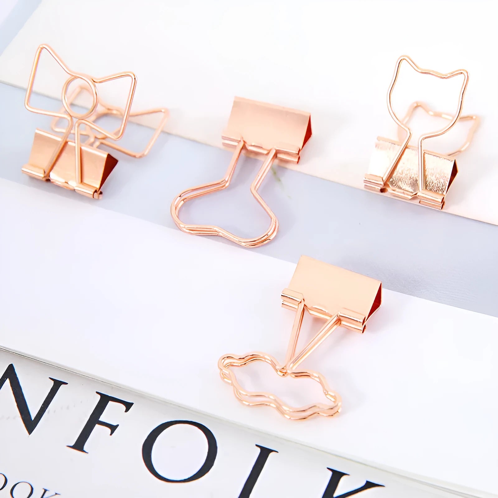 Small gold metal paper clip with a decorative bow charm attached.