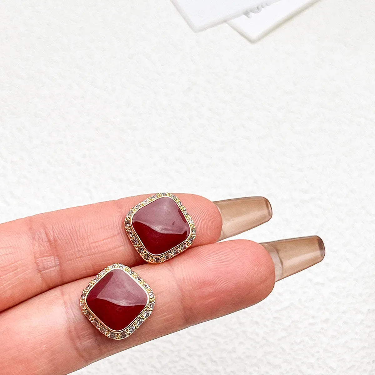 Red alloy square earrings with an inlaid geometric pattern, shown from the front.
