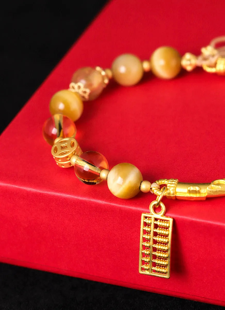 Close-up of handmade abacus bracelet with tigereye, citrine, and yellow tower crystal beads in a diamond shape on a wrist.