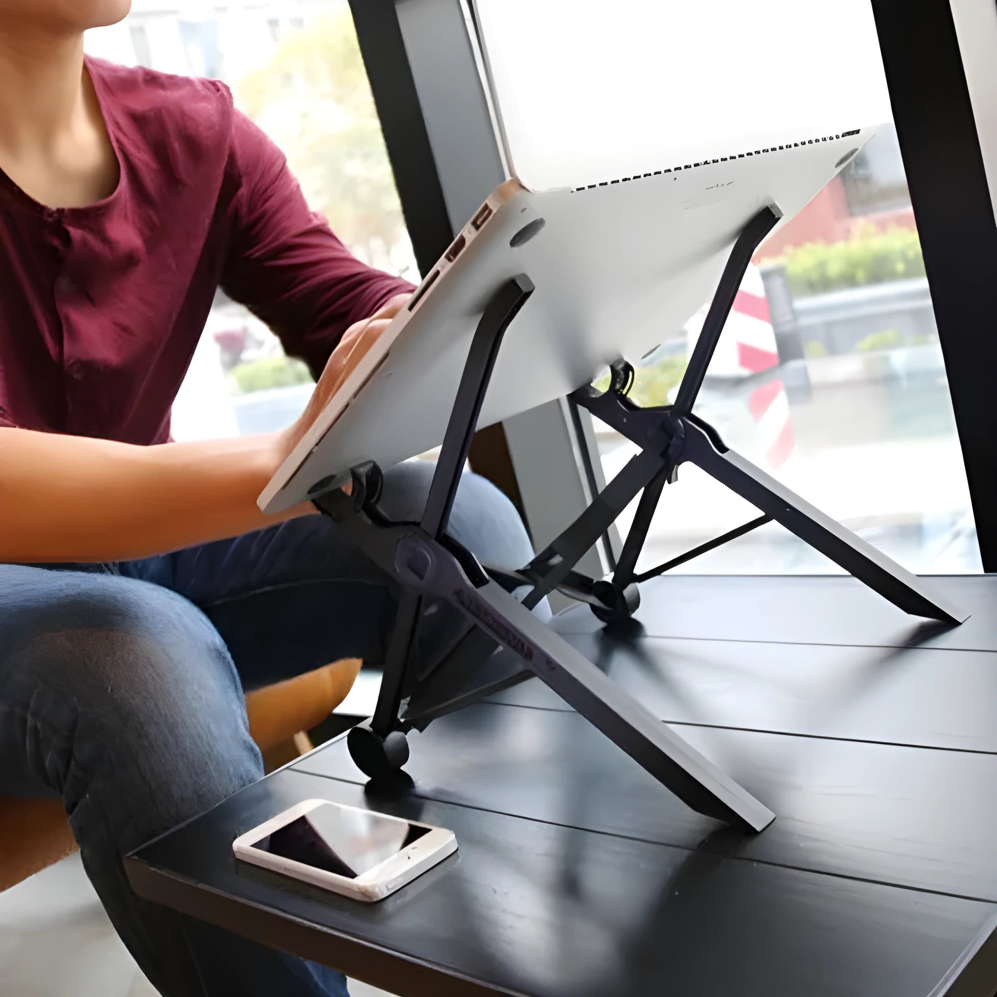 Sagacious black portable folding laptop stand with collapsed legs next to its carrying case.
