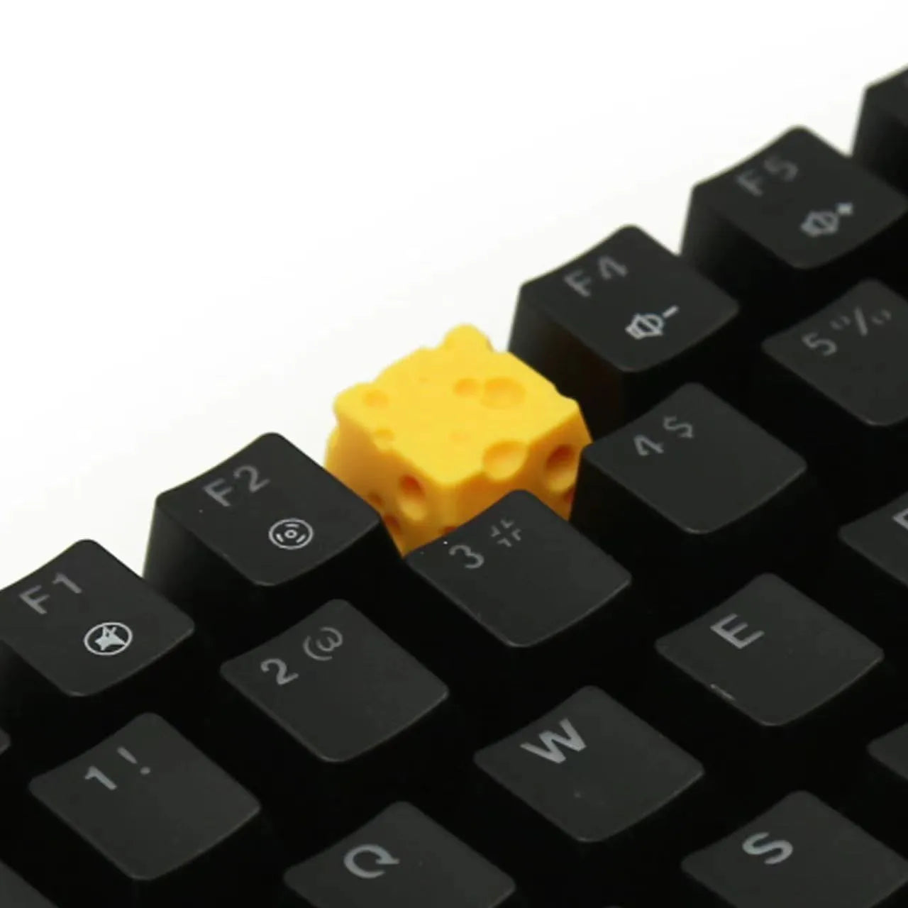 Close-up of a bright yellow resin key cap with a detailed sculpted cheese design.