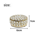 French gold iron jewelry storage box with a clear crystal glass lid on a wooden surface.