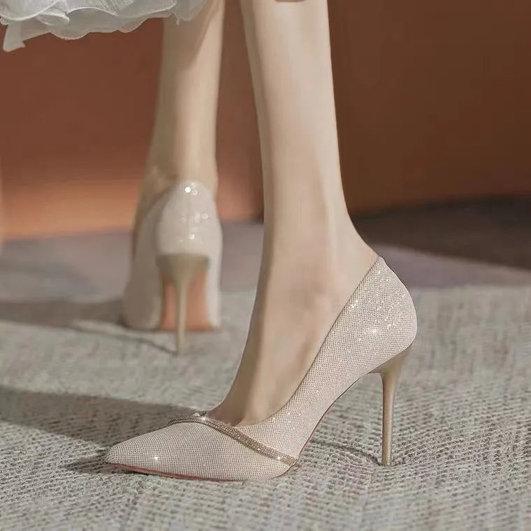 Gold women's stiletto pointed toe high heels on a plain background.