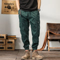 Man wearing khaki loose-fit cotton harem pants with tapered ankle-banded legs.