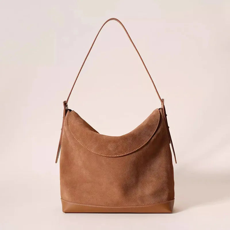 Light brown genuine leather women's retro shoulder bag with clamshell opening on a table.