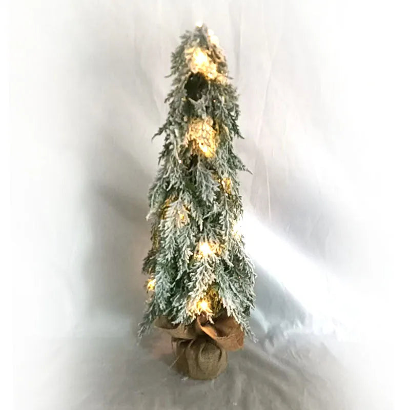 Small 24-inch artificial Christmas tree with lights and snow finish on desktop