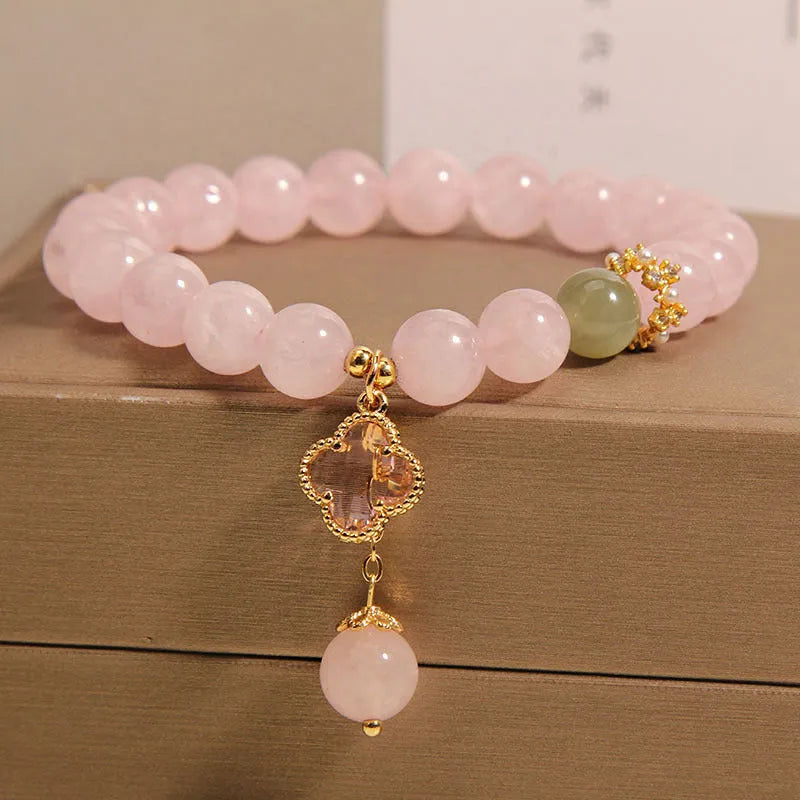 Pink women's bracelet with a crystal four-leaf clover pendant and rhinestone details on an adjustable chain.