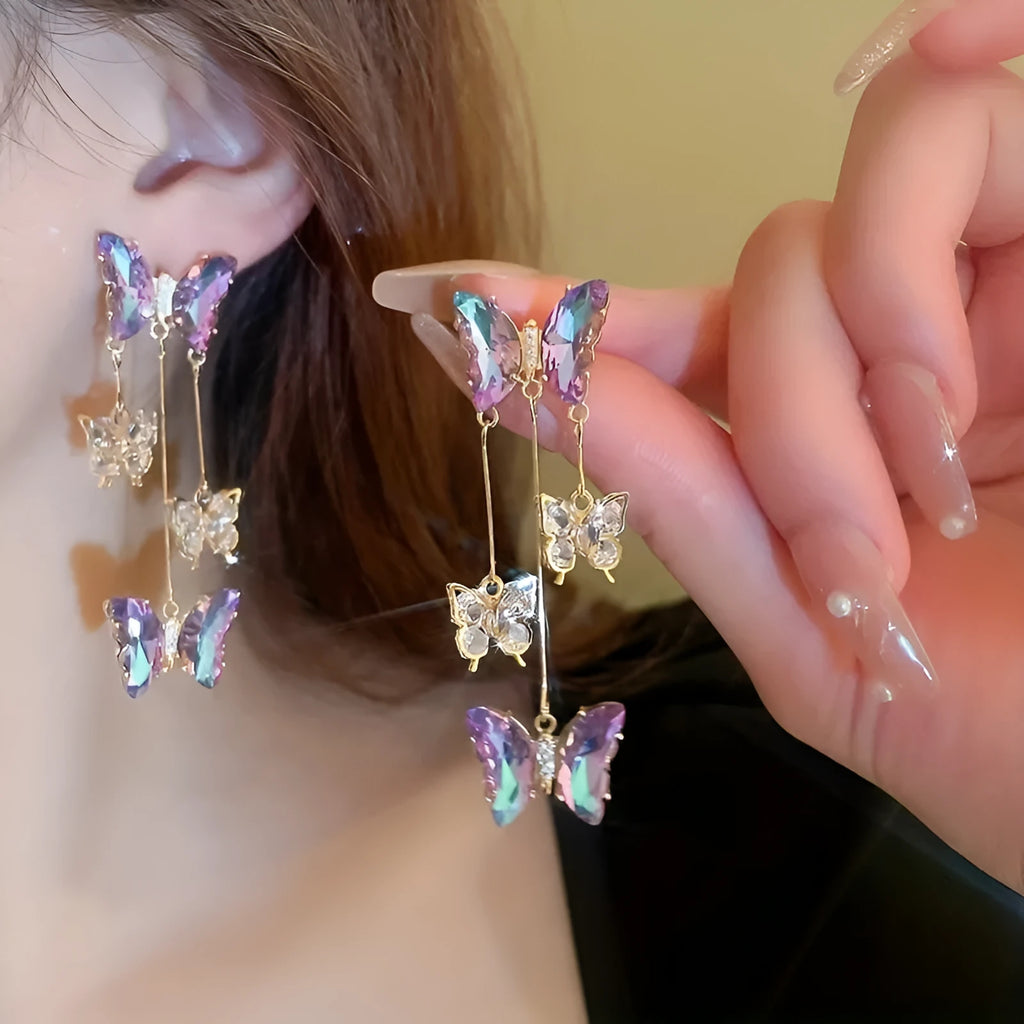 A pair of silver and blue purple butterfly tassel earrings with crystal flowers and droplet pendants.